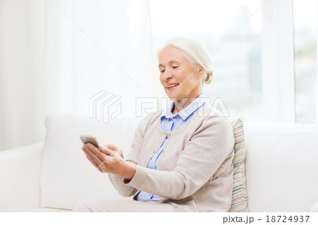 senior woman with smartphone texting at home 18724937