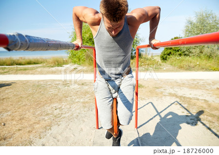 young man exercising on parallel bars outdoors young man exercising on parallel bars outdoors 18726000