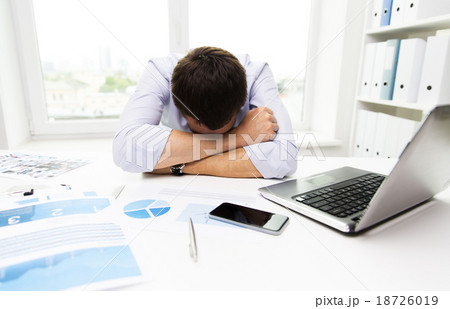 businessman with laptop and papers in office 18726019