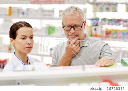 pharmacist showing drug to senior man at pharmacy 18726333