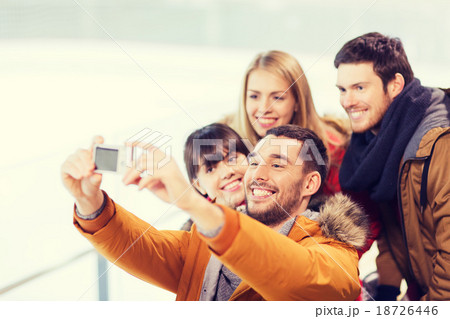 happy friends with camera on skating rink 18726446
