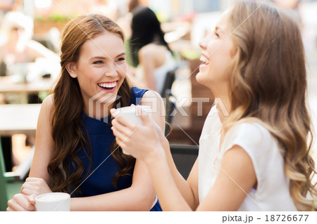 smiling young women with coffee cups at cafe 18726677