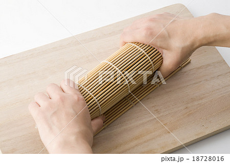 太巻きの作り方　巻きすを押さえてしっかりと形を整える 18728016