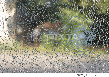 Broken window with a bullet hole in the middle 18735997
