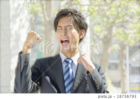 屋外でガッツポーズをする若い男性サラリーマン 18736793