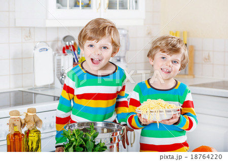 Two little kid boys eating spaghetti in domestic 18764220