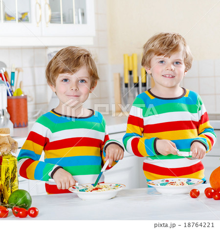 Two little kid boys eating spaghetti in domestic 18764221