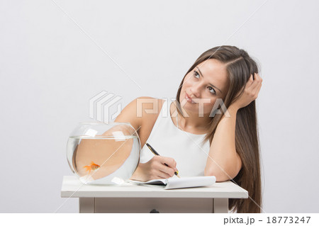 Girl thoughtfully writing in a notebook, standing  18773247