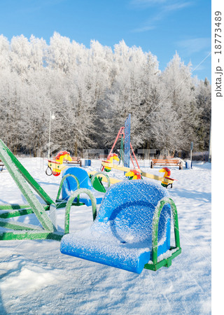 snow covered swing and slide at playground snow covered swing and slide at playground 18773489