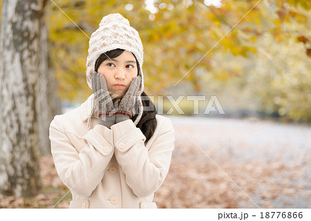 紅葉した公園の並木道に立っているコートを着た10代の女性 18776866