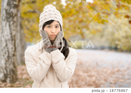 紅葉した公園の並木道に立っているコートを着た10代の女性 18776867