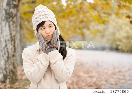 紅葉した公園の並木道に立っているコートを着た10代の女性 18776869