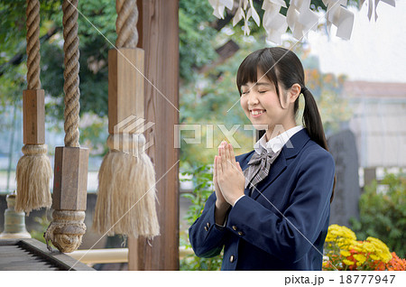 神社でお祈りしている制服姿の女子高生の写真素材