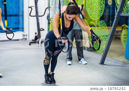 Young woman training exercise push ups with trx Young woman training exercise push ups with trx 18791282