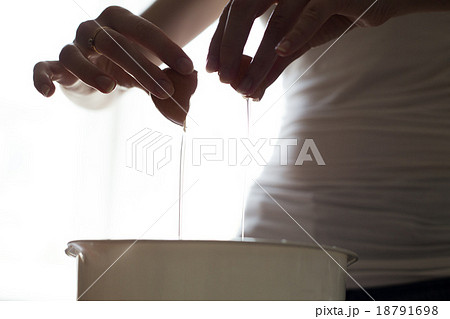 hands opening broken eggshell of brown raw egg 18791698