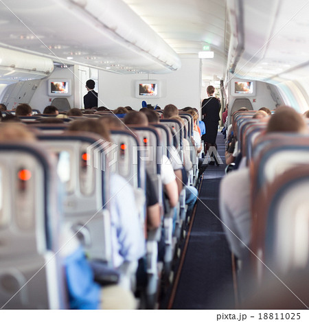Interior of airplane with passengers on seats. 18811025