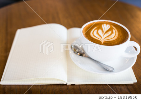 Hot latte art coffee cup on wooden table and note book, vintage Hot latte art coffee cup on wooden table and note book, vintage 18819950