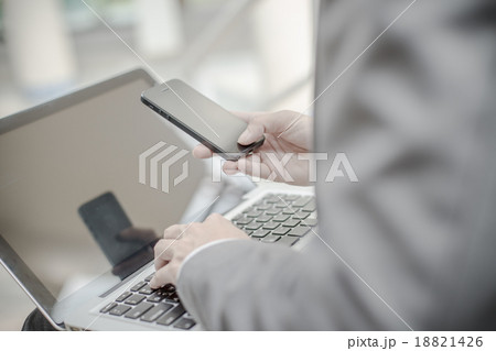 Businessman using laptop pc and mobile phone. He is sitting on a 18821426