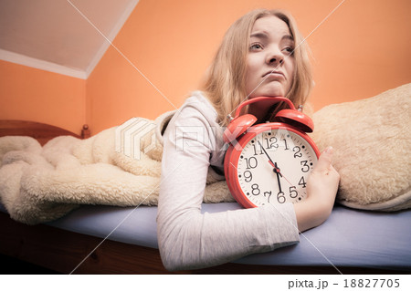 Unhappy girl in bed with alarm clock Unhappy girl in bed with alarm clock 18827705