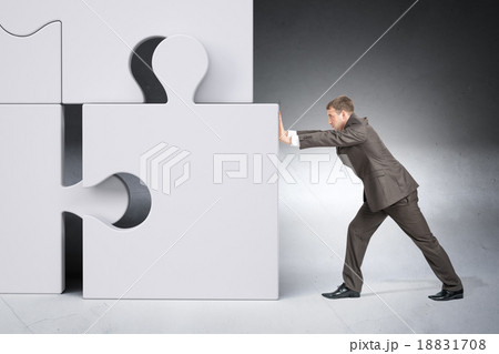 Man in suit pushing grey puzzle piece 18831708