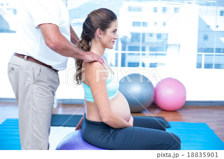 Midsection of instructor helping pregnant woman Midsection of instructor helping pregnant woman 18835901