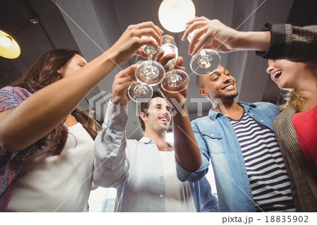 Low angle view of happy colleagues toasting with champagne 18835902