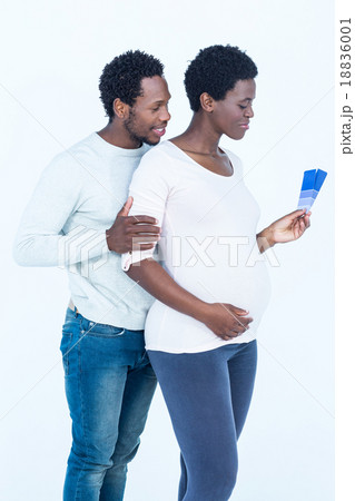 Pregnant wife holding color swatches while standing with husband 18836001