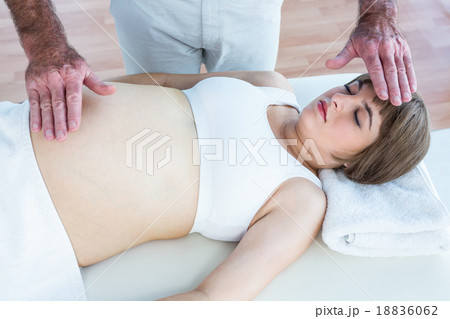 Pregnant woman getting reiki from male therapist Pregnant woman getting reiki from male therapist 18836062