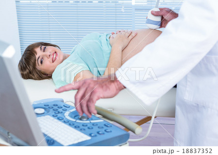 Doctor showing ultrasound monitor to happy pregnant woman 18837352