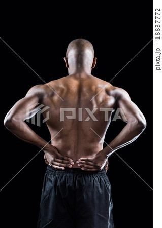 Rear view of muscular athlete stretching with hand on hip 18837772