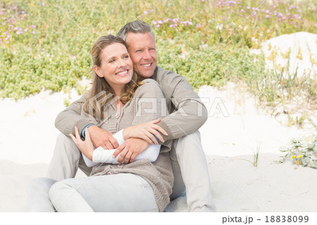 Happy couple sitting on the sand Happy couple sitting on the sand 18838099