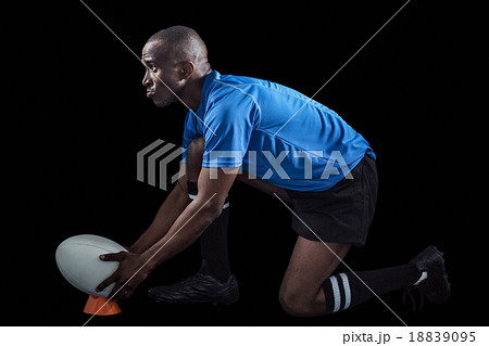 Confident rugby player looking away while keeping ball on kickin Confident rugby player looking away while keeping ball on kickin 18839095