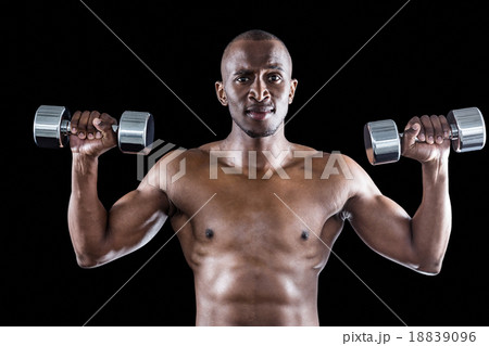 Portrait of athlete lifting dumbbell while exercising 18839096