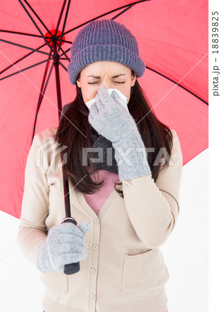 Sick brunette blowing her nose while holding an umbrella Sick brunette blowing her nose while holding an umbrella 18839825