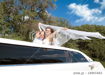 Bride and groom standing in Limo waving 18865883