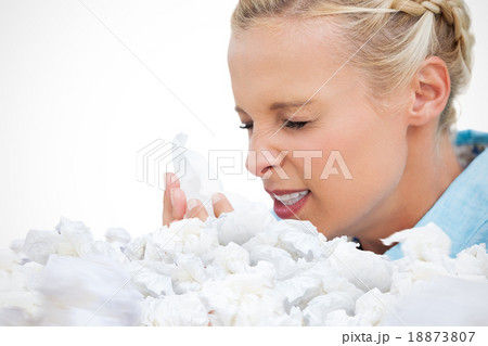 Composite image of ill woman sneezing into tissue Composite image of ill woman sneezing into tissue 18873807