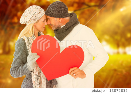Composite image of couple holding heart while looking at each ot 18873855