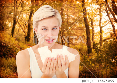 Composite image of sick woman holding tissues looking at camera Composite image of sick woman holding tissues looking at camera 18875055