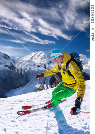 Skier skiing downhill in high mountains against bl Skier skiing downhill in high mountains against bl 18891103
