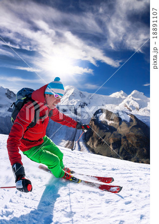 Skier skiing downhill in high mountains against bl Skier skiing downhill in high mountains against bl 18891107