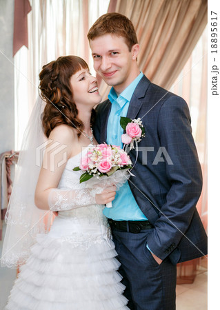 Portrait of the groom and the bride near a window 18895617