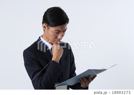 顎に手をやるビジネスマンの写真素材