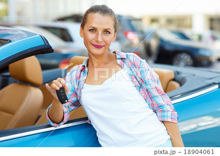 Young woman standing near a convertible with keys in hand Young woman standing near a convertible with keys in hand 18904061