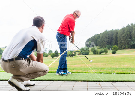 Golf trainer working with golf player  18904306