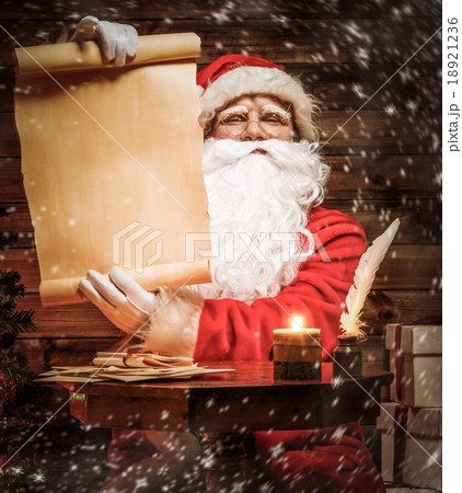 Santa Claus in wooden home interior reading wish list scroll 18921236