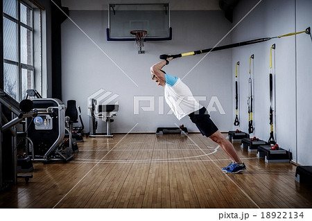 Attractive man during workout with suspension straps In The Gym's Studio Attractive man during workout with suspension straps In The Gym's Studio 18922134