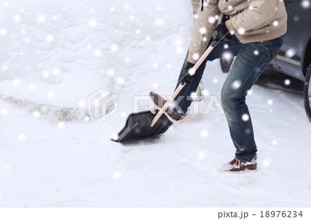 closeup of man digging snow with shovel near car closeup of man digging snow with shovel near car 18976234