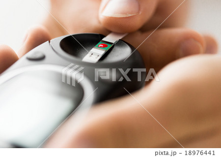 close up of man checking blood sugar by glucometer close up of man checking blood sugar by glucometer 18976441