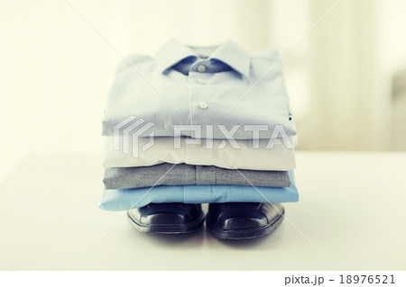 close up of folded male shirts and shoes on table 18976521