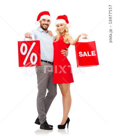 happy couple in santa hats with red shopping bags 18977557